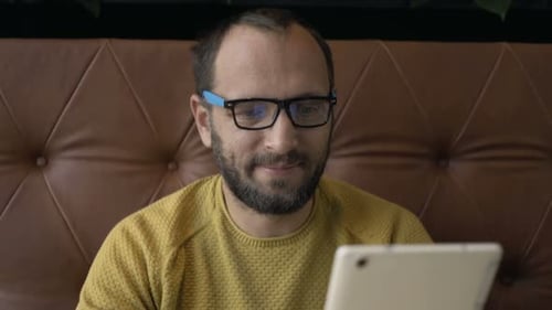 Young Man Using Tablet Computer Sitting in Cafe 30s
