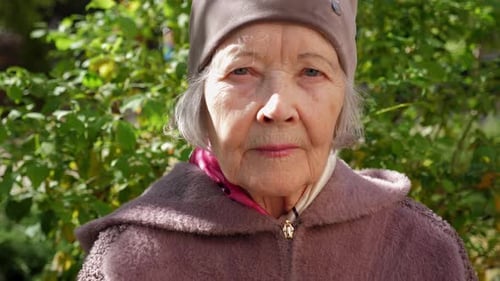 Portrait of an Elderly Grandmother with Gray Hair in a Hat in the Park in Autumn