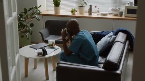 Man in Scrubs Drinking Coffee at Home