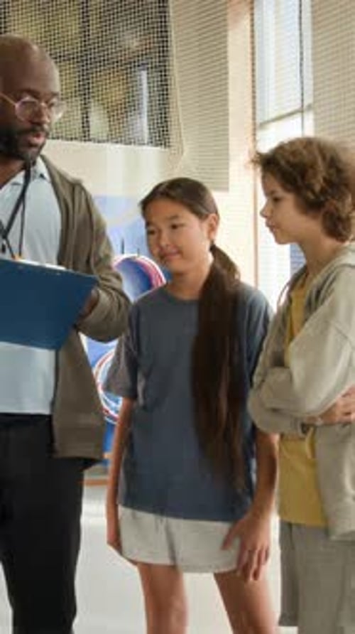 African American Man as Coach with Kids in Indoor Gym Vertical