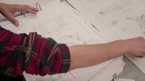 Hand points at architectural blueprints