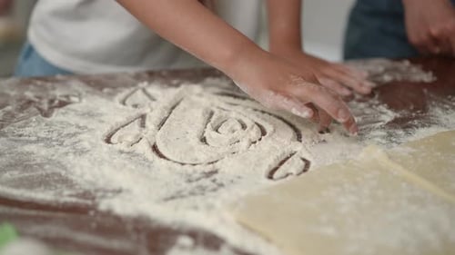 Child Drawing Hearts in Flour While Baking at Home