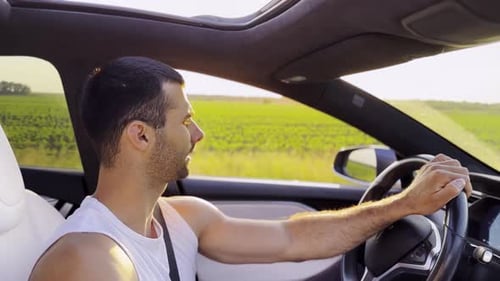 Man Driving Car Through Countryside on Sunny Day