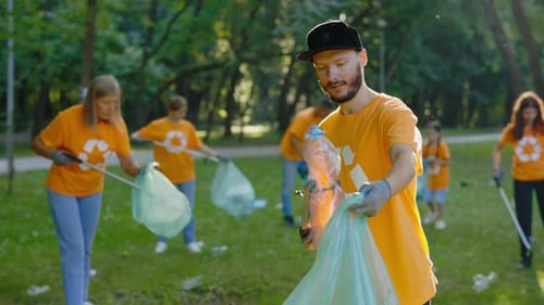 Diverse Eco Volunteers in Tshirts with Recycling Symbol Picking Up Plastic Garbage Cleaning the