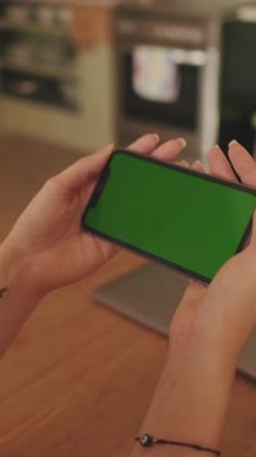Close-up of young woman's hands using mobile phone green screen chroma key at home