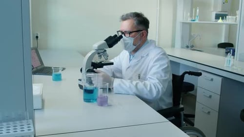 Scientist at Microscope in Lab Wearing Mask