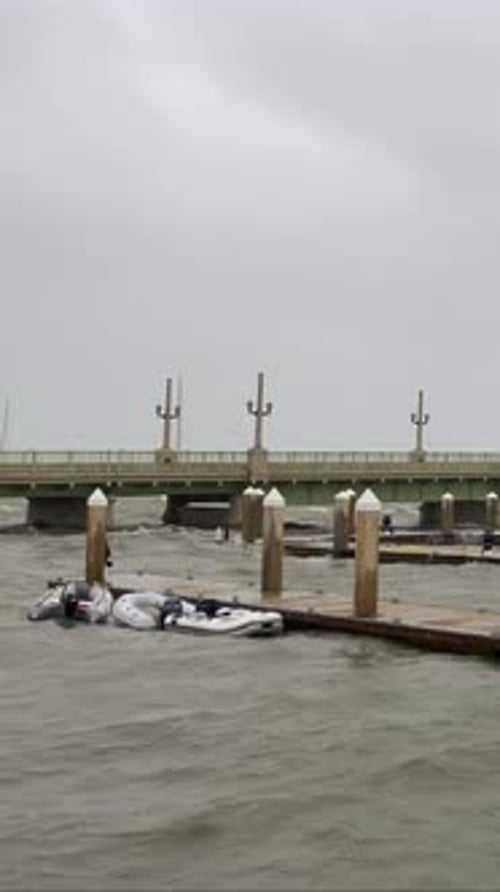 Hurricane storm surge rough water waves battering boat dock marina, overcast