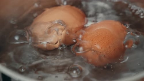 Zwei kochende Eier in einem Topf mit sprudelndem Wasser. Nahaufnahme. 4K