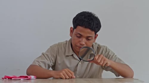Jeune homme examinant intensément un bureau avec une loupe et un chiffon de nettoyage, comportement obsessionnel-compulsif