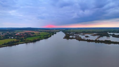An evening panoramic landscape of a lake and rugged shores with islands.