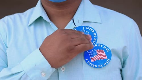 Person Applies "I Voted By Mail" Stickers