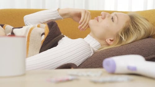 Sick Woman Lying on Sofa at Home