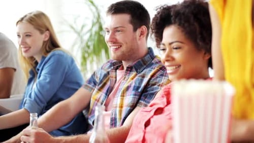 Concept d'amitié, de loisirs, de personnes et de divertissement - Des amis heureux mangeant du pop-corn, buvant
