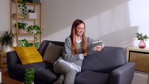 Woman Relaxing on Couch Using Tablet Device