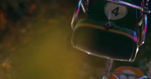 Empty plastic metal chairs hang below spinning carnival attraction ride, telephoto nobody