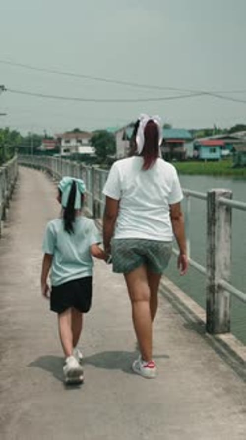 Family Members Enjoying a Walk Across a Bridge in Thailand