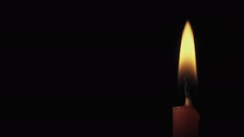 Red candle on a black background, in motion, slider shot, extinguish a candle, smoke from a candle,