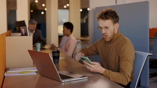 Man Reacts to News on Phone in Office