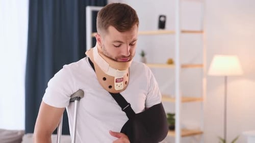 Man with Injured Arm and Neck Using Crutches