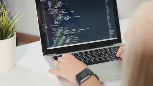 Programadora mujer que escribe el código HTML del programa sentada en el lugar de trabajo en la oficina