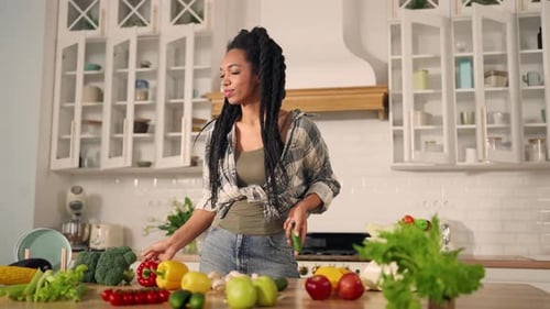Woman Juggling Fresh Produce in Bright Kitchen