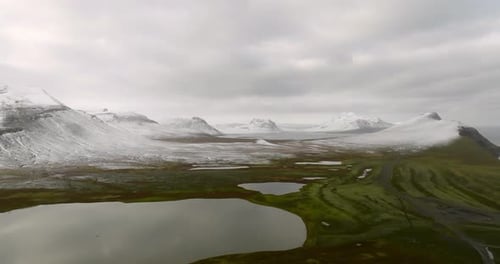 scenic icelandic landscape view on rocky shore ocean, snowy mountains and green grass