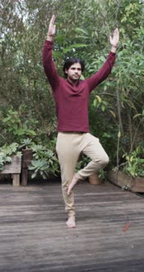 Vertical video of biracial man practicing yoga on terrace in nature, slow motion