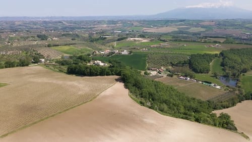 Weitwinkel-Drohnenaufnahme, die einen schönen Blick auf ein Tal mit Ackerland, Weingütern und Medien nach oben schwenkt