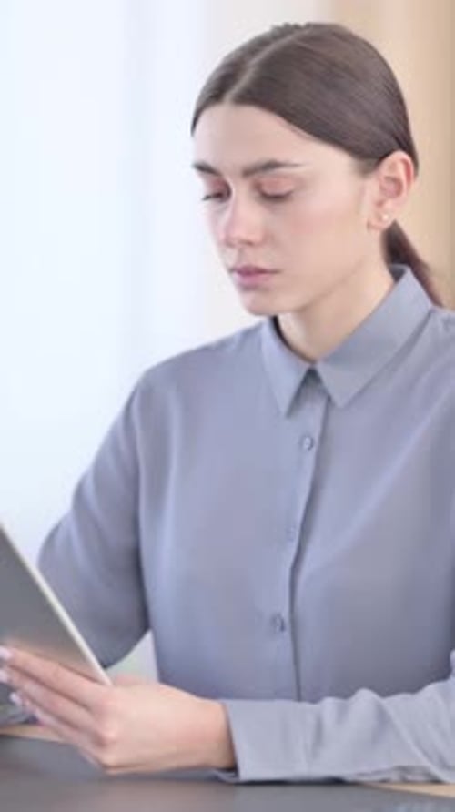 Woman Using a Tablet at a Desk Indoors