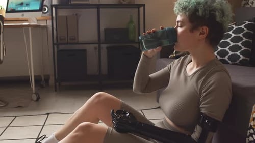 Woman with Prosthetic Arm Drinking Water at Home