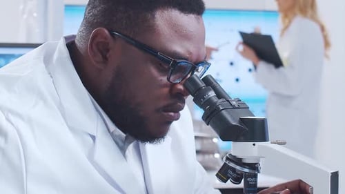 Scientist Examines Sample Under Microscope in Modern Lab