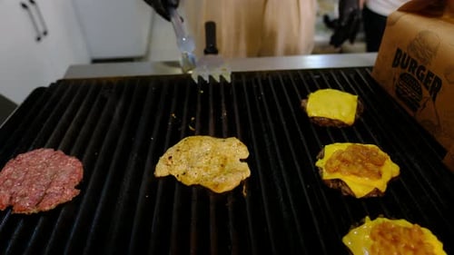 Hamburger Patties and Toppings Cooking on a Grill