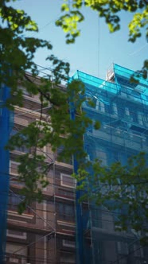 A Dynamic Urban Construction Scene Showcasing Renovation Efforts Accompanied By Blue Netting and