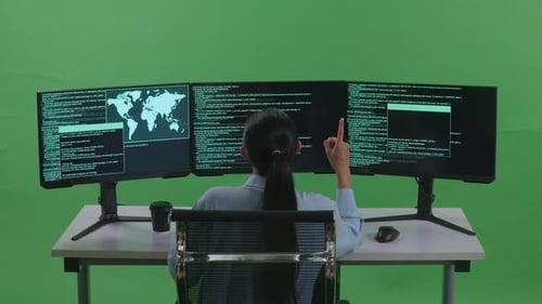 Back View Of Asian Woman Developer Thinking While Write Code With Multiple Screens In Green Screen