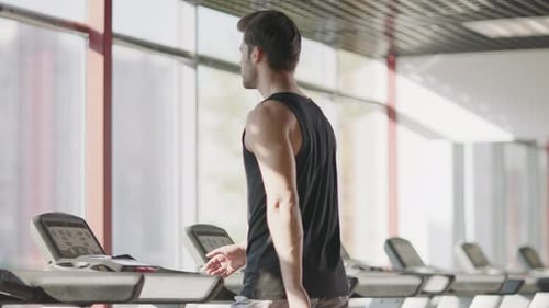 Athlete Man Walking On Treadmill In Fitness Center. Fitness Man Training On Running Machine In Gy...