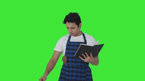 Serious Indian cook making food from recipe book Green screen