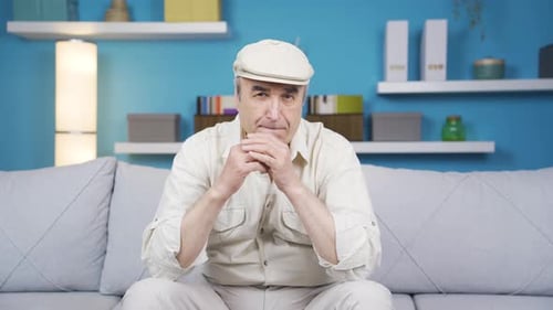 Un vieil homme frustré et pensif est assis seul à la maison et envisage la vie seul.