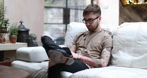 Young Man Relaxing on Couch Using Mobile Phone