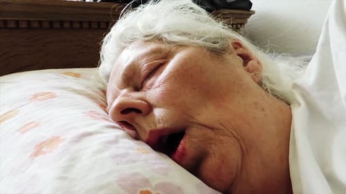 Close-up View of Tired Elderly Woman Sleeping in Bed - Handheld Steady Shot