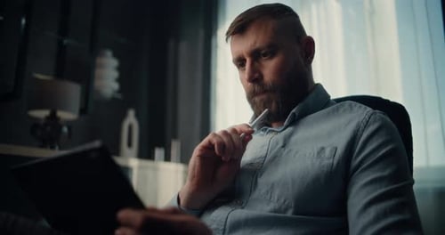 Thoughtful Financial Analyst Working on Tablet Computer with Digital Stylus Monitoring RealTime