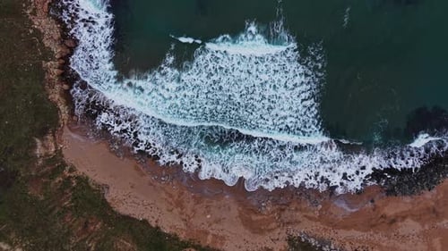 Waves crash on the shore at an empty beach during daylight hours