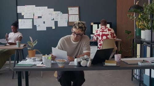 Male UX Designer Working on UI of Mobile App Typing on Laptop at Office Desk