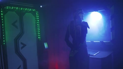 Woman in metal armor, with long dreadlocks is standing and looking into the porthole, 4k