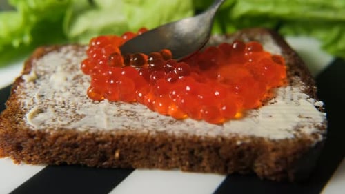 Preparing Appetizing Sandwich with Red Caviar and Butter