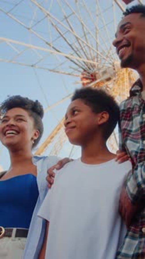 Two Adults Standing with Kid While Looking at Roller Coaster