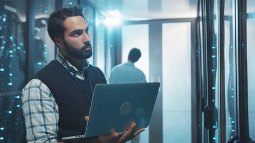 Man Working on Laptop in Server Room