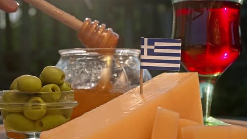 Queijo grego tradicional, azeitonas, mel e vinho tinto são apresentados sob luz solar suave para uma comida autêntica
