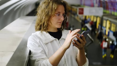 Portrait of a young woman using mobile phone in the subway.