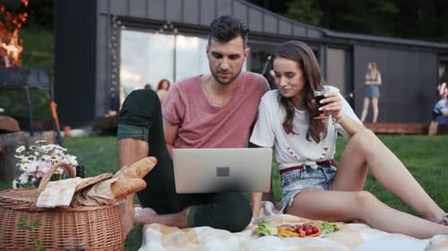 Couple Enjoying Picnic and Laptop on a Blanket