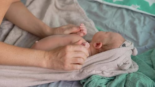 Person Massaging Adorable Newborn Baby Indoors